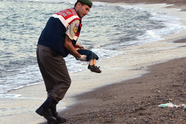 A paramilitary police officer carries the body of Aylan Kurdi, who drowned last September