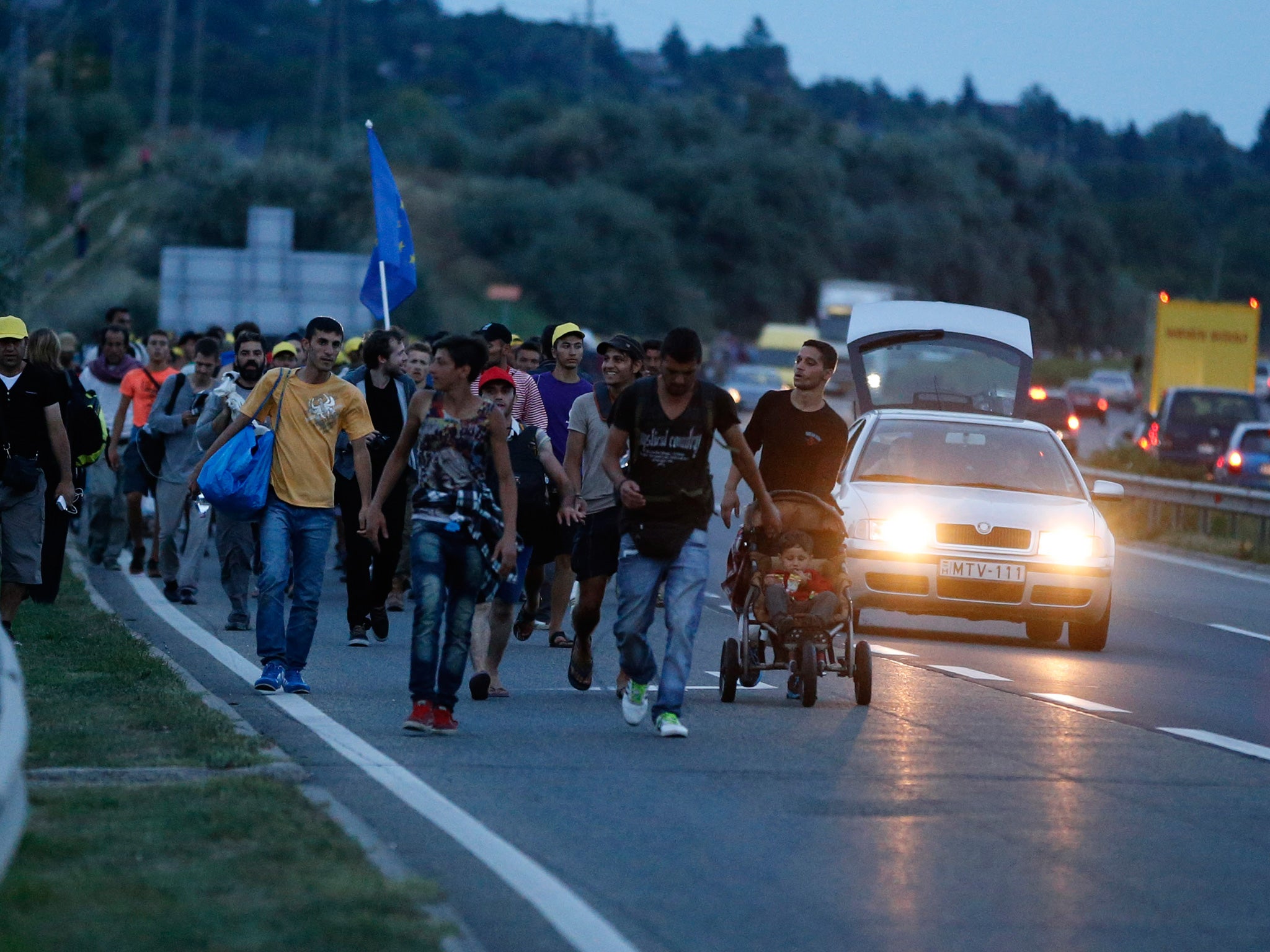 Refugees walk in a long track on the highway near Budapest, Hungary