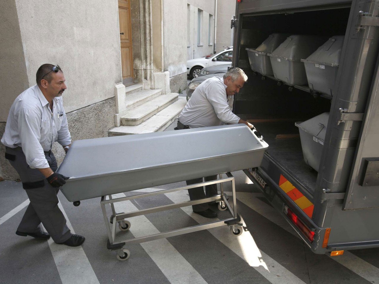 Coffins with bodies of migrants who died in an abandoned lorry are unloaded from a van on August 28, 2015 for an investigation at a forensics institute in Vienna.
