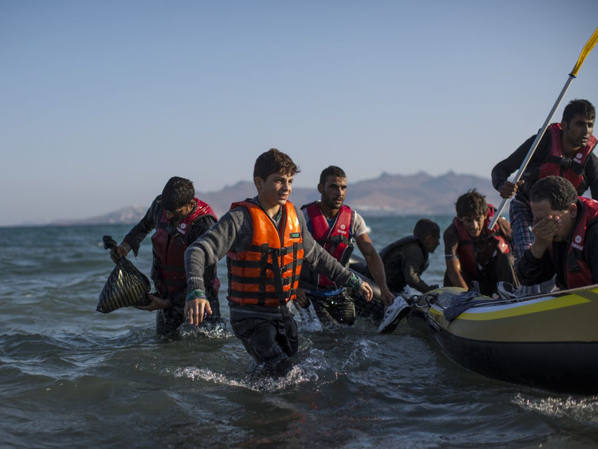A group of refugees on an inflatable dinghy reach the beach at Kos