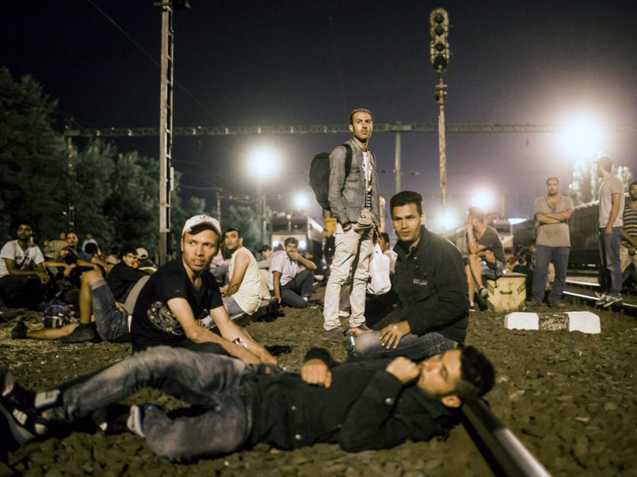 Refugees rest on a track at the Tatabanya Railway Station near Budapest in Hungary on their way to Austria (EPA)