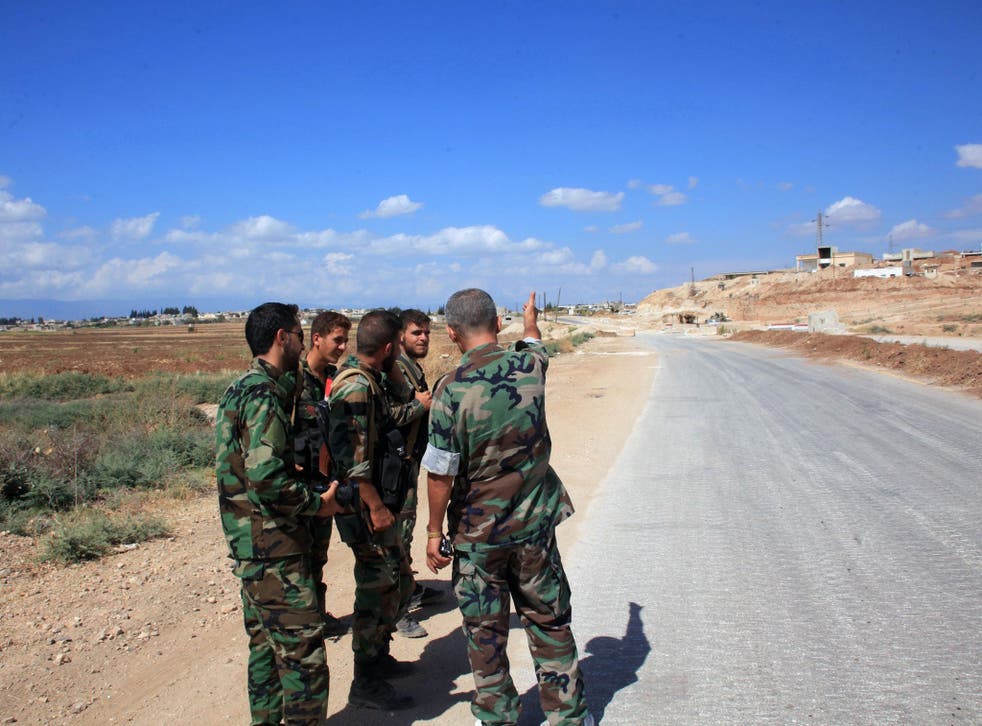 Syrian government forces patrol a road linking two towns together in Syria's central Hama province last year