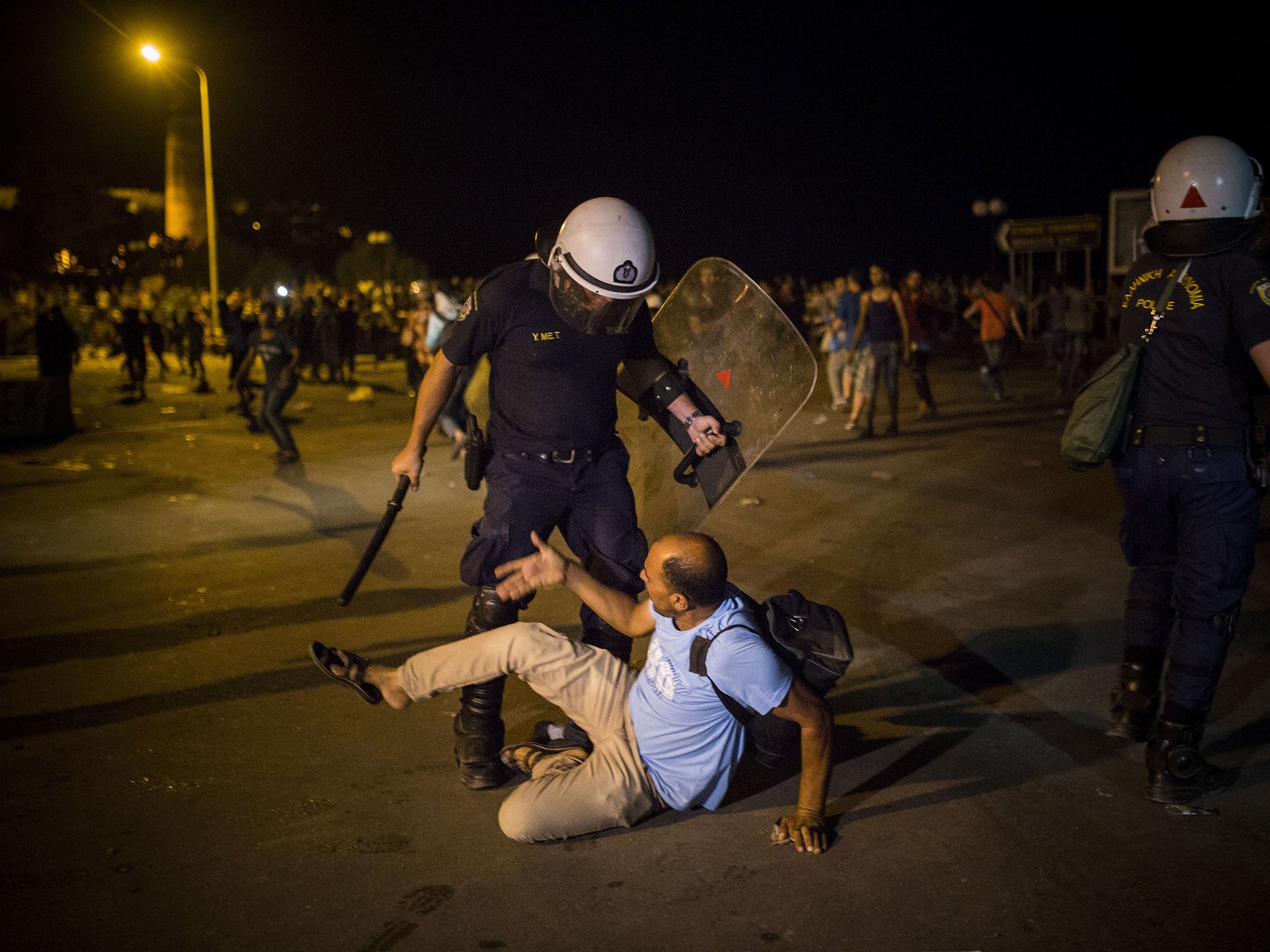 A migrant is confronted by a riot office during protests on the Greek island of lesbos on Saturday night, 5 September