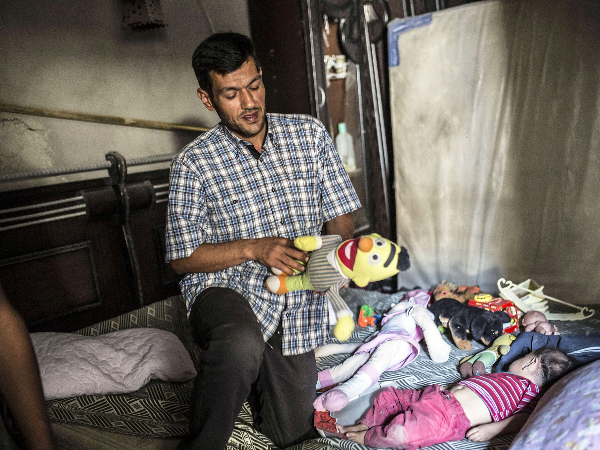 Abdullah Kurdi holds a toy as he visits Aylan's room in his home in Kobane