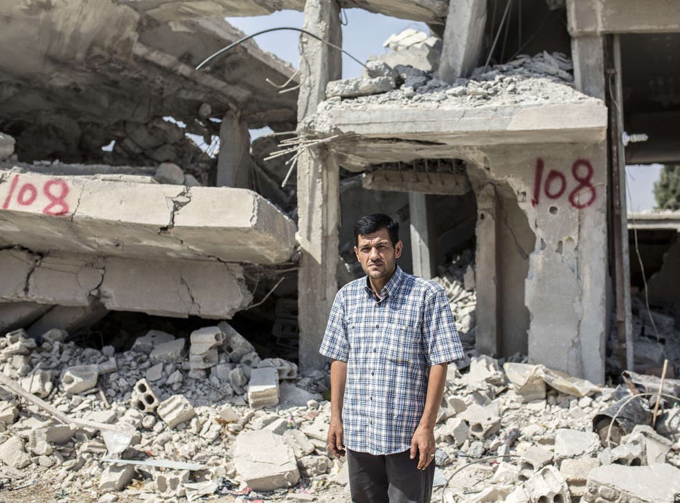 Abdullah Kurdi stands in front of his neighbour's house in Kobane