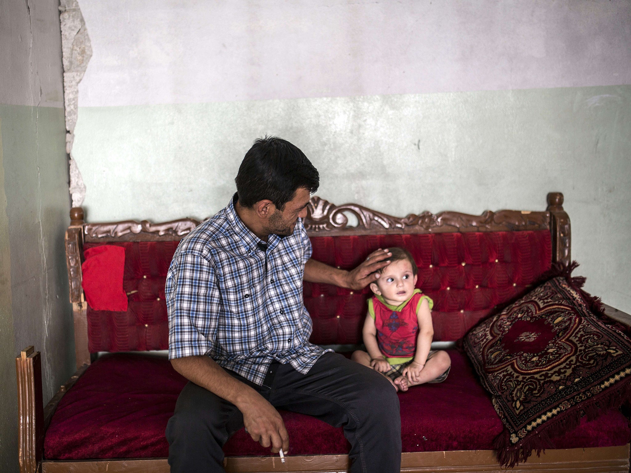 Abdullah Kurdi sits next to his nephew in a relative's house in Kobane