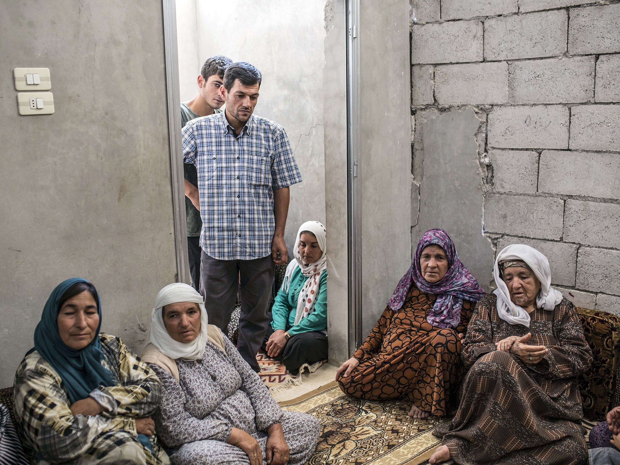 Abdullah Kurdi stands next to neighbors in his house in Kobane