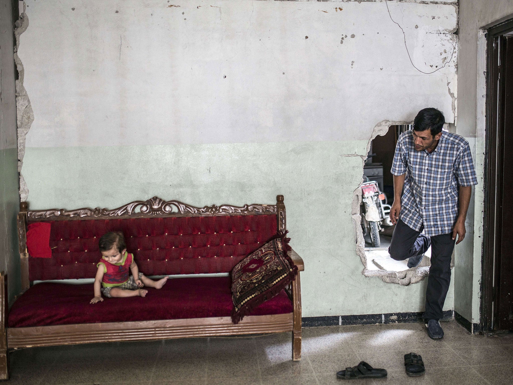 Abdullah Kurdi enters a neighbour's damaged home in Kobani, where his nephew of a similar age to Aylan Kurdi is sitting