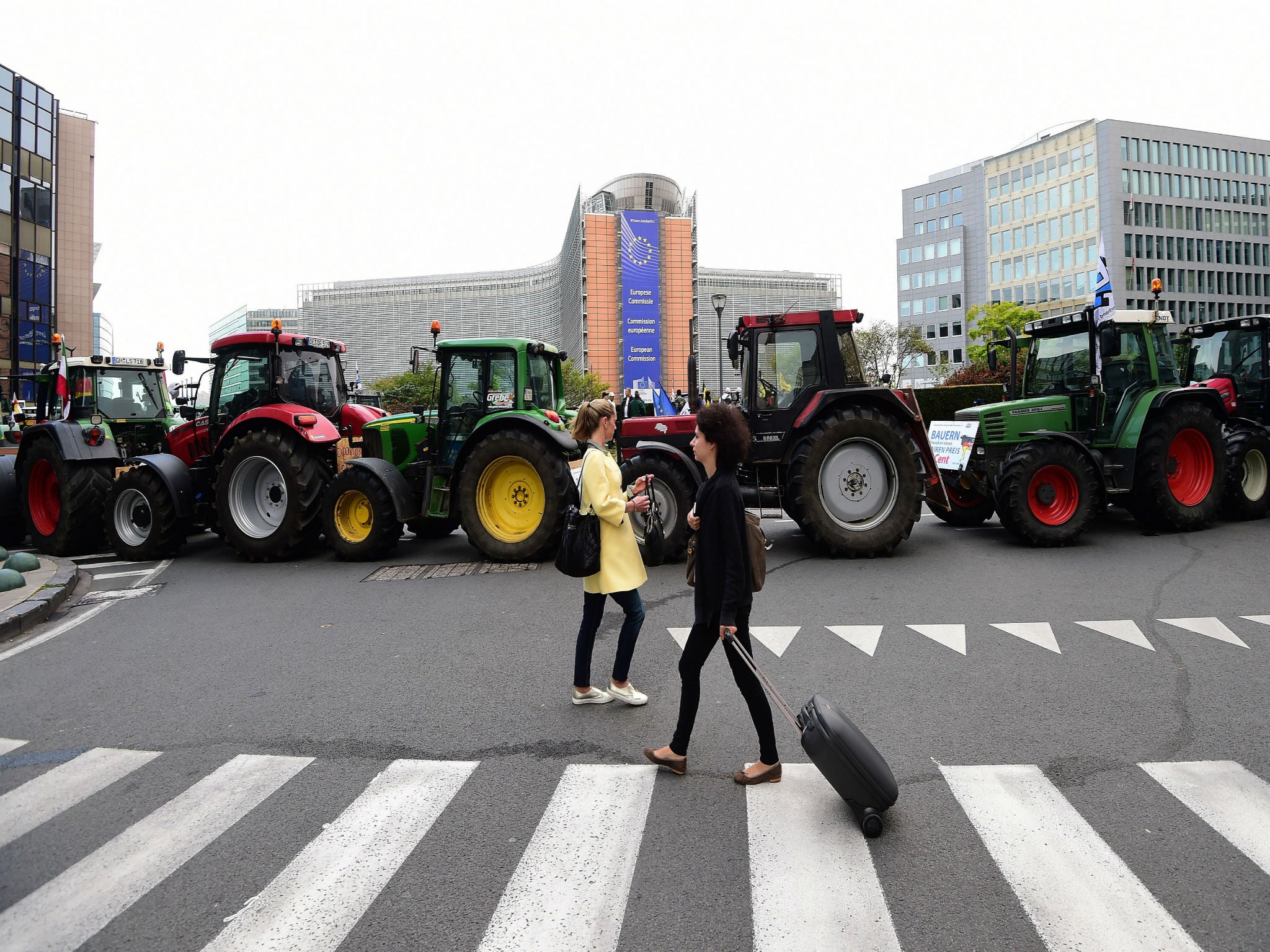 People walk past tractors parked in front of the European Commission during a farmers demonstration protesting against plunging food prices and soaring costs as European agriculture ministers hold an extraordinary meeting at the European Council on Septem