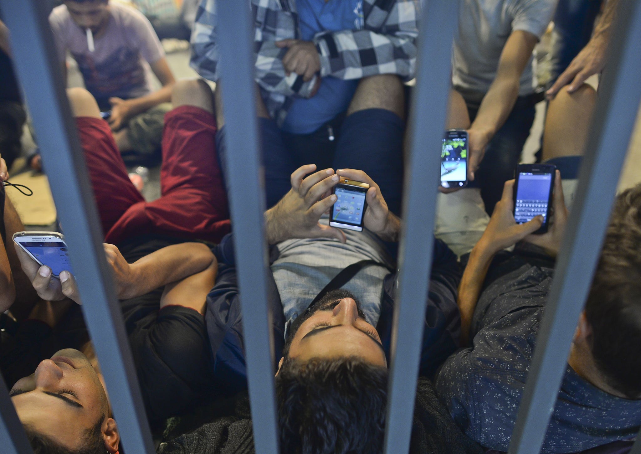 Refugees at Budapest Railway station check their phones