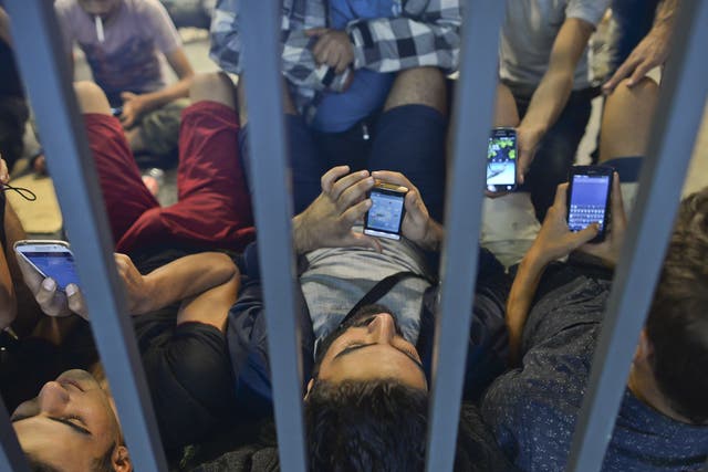 Refugees at Budapest Railway station check their phones