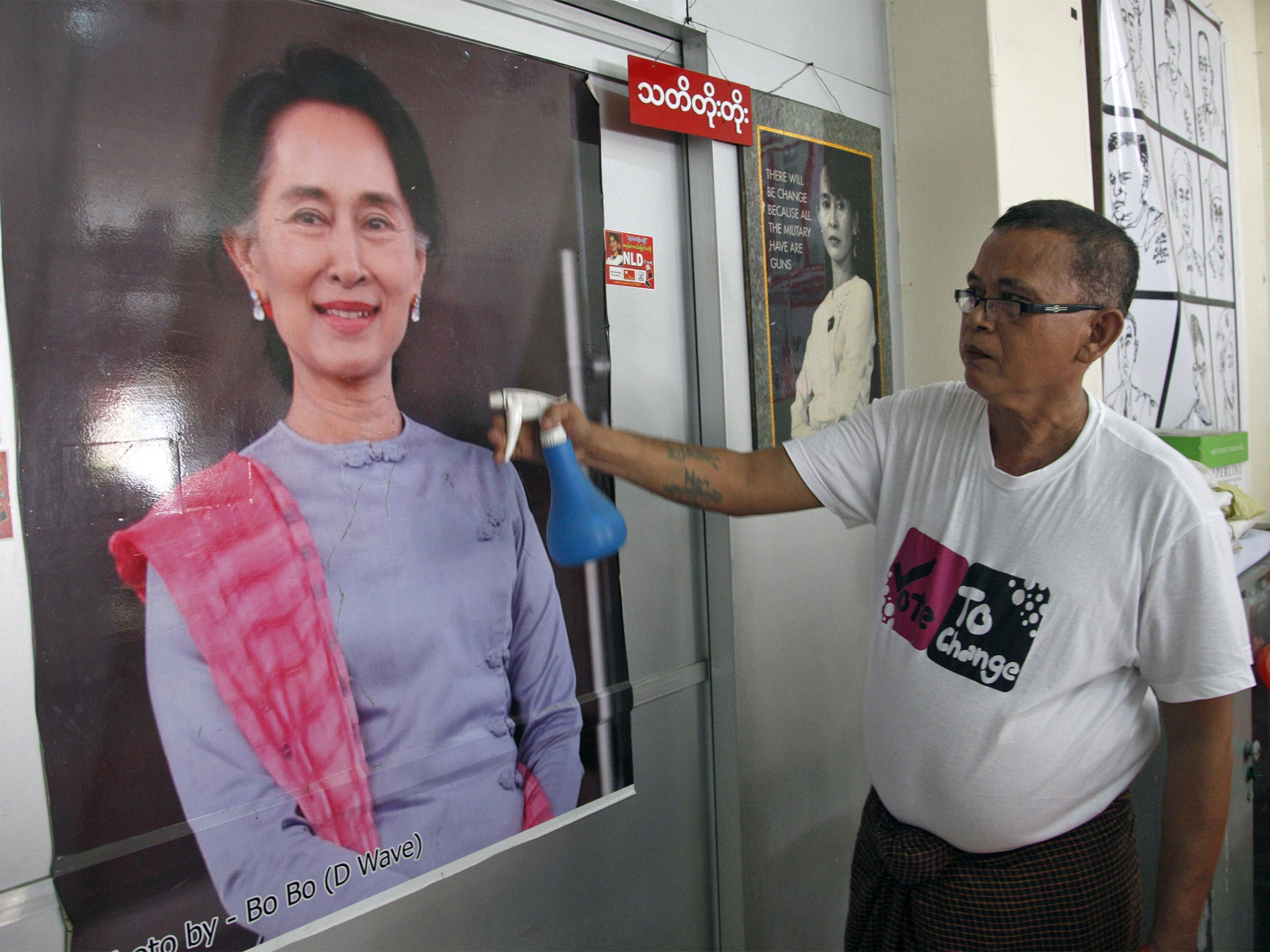 A supporter cleans a portrait of Aung San Suu Kyi at the NLD’s headquarters in Yangon