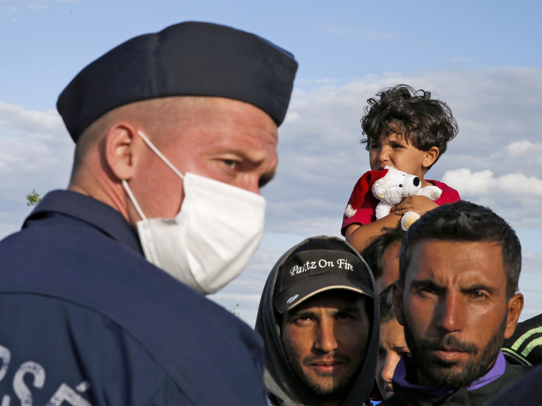 A Hungarian police officer stands in front of migrants wishing to leave a collection point in the village of Roszke, Hungary