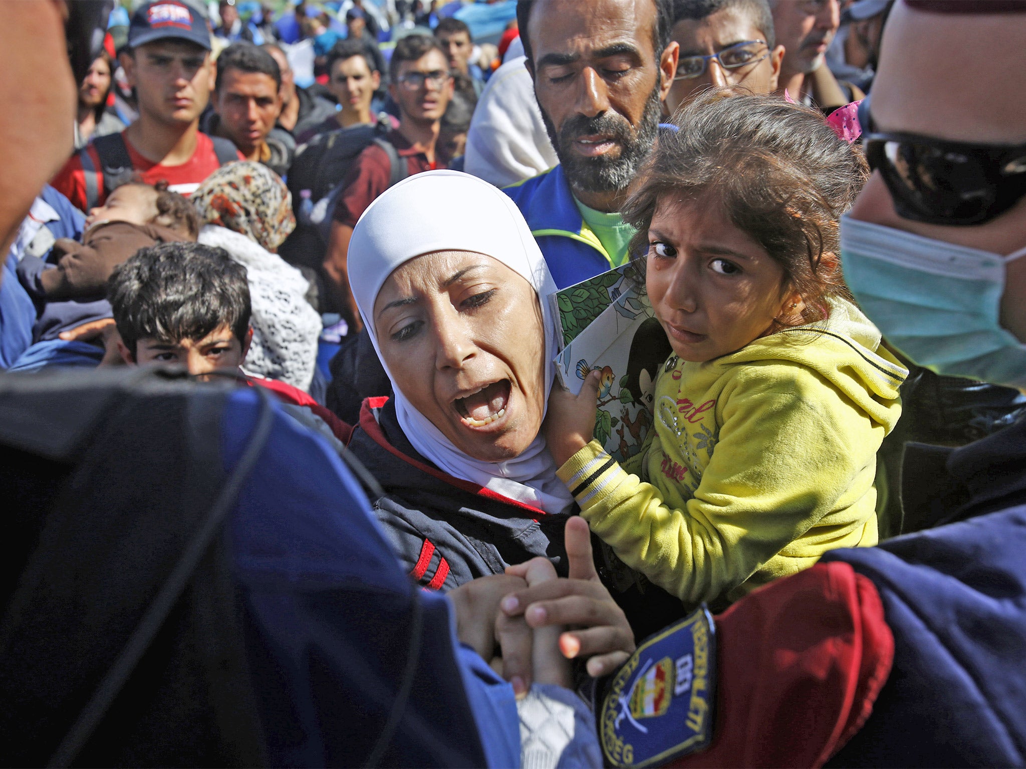 A migrant woman holds a child as she tries to talk to Hungarian police officers in Roszke