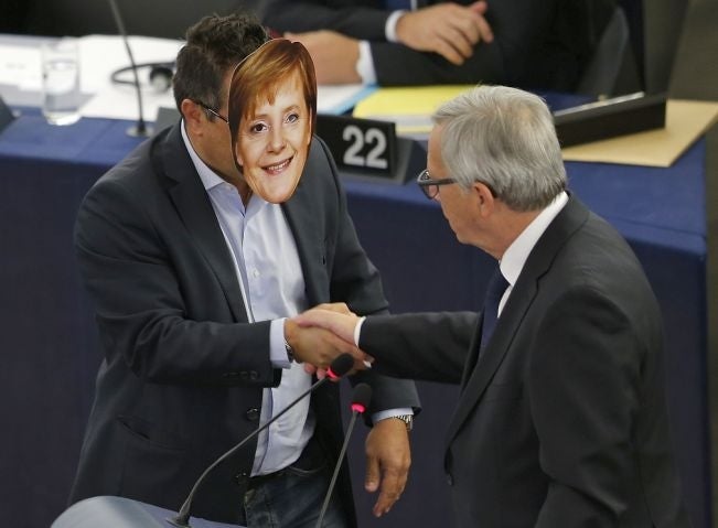 Italian Member of the European Parliament Gianluca Buonanno (L) wears a mask depicting German Chancellor Angela Merkel as he shakes hands with European Commission President Jean-Claude Juncker during his address to the European Parliament in Strasbourg, F