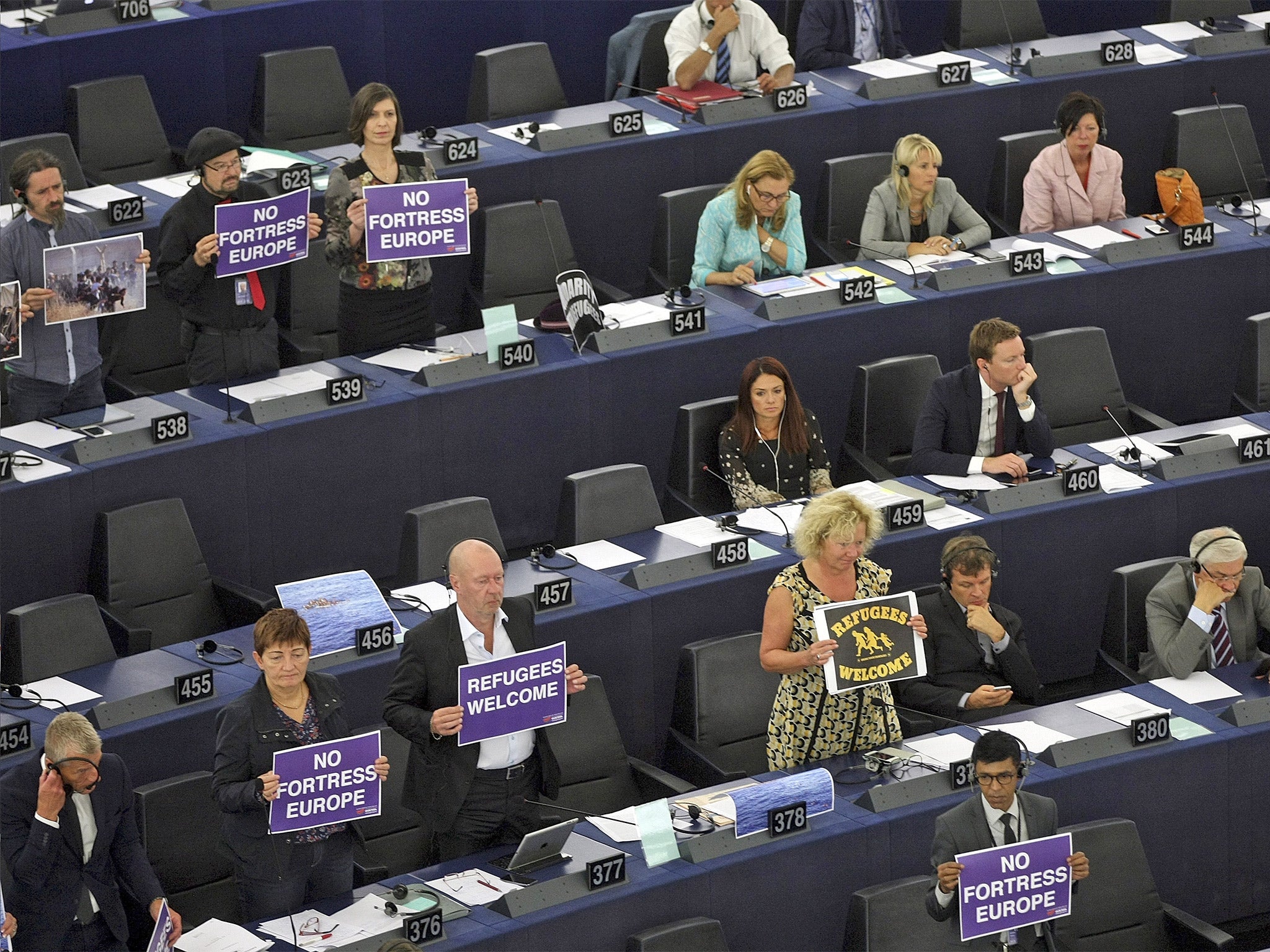 MEPs hold posters while Jean-Claude Juncker delivers his address