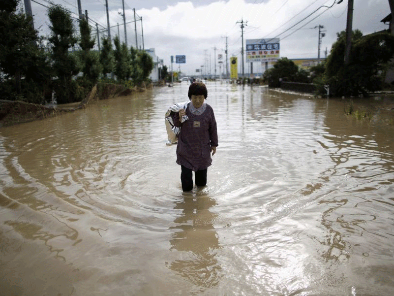 A woman wades through a residential area flooded in Joso, Ibaraki