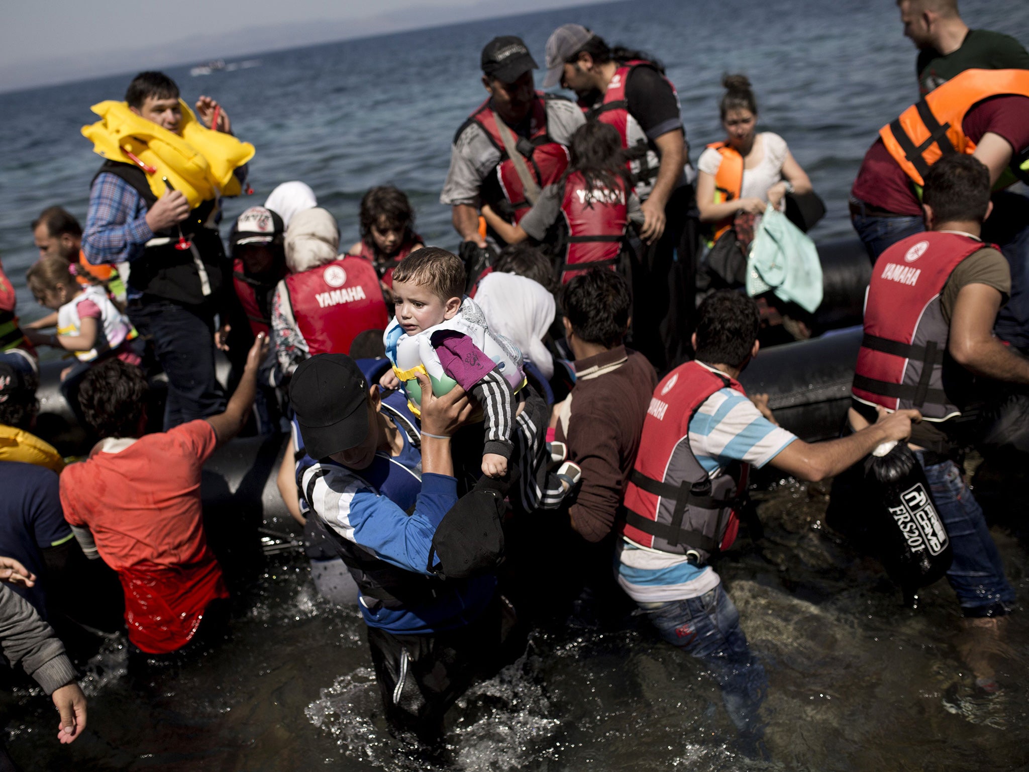 Syrian refugees arrive on the shores of the Greek island of Lesbos after crossing the Aegean Sea from Turkey on a inflatable dinghy on September 11, 2015
