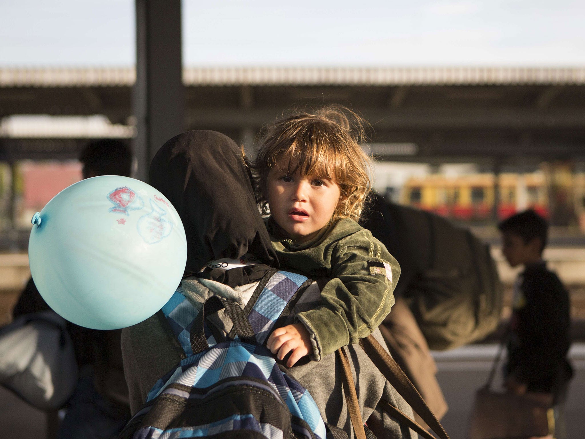 A refugee holds a child after getting out of a special train coming from Munich upon arrival at the railway station in Berlin Schoenefeld 