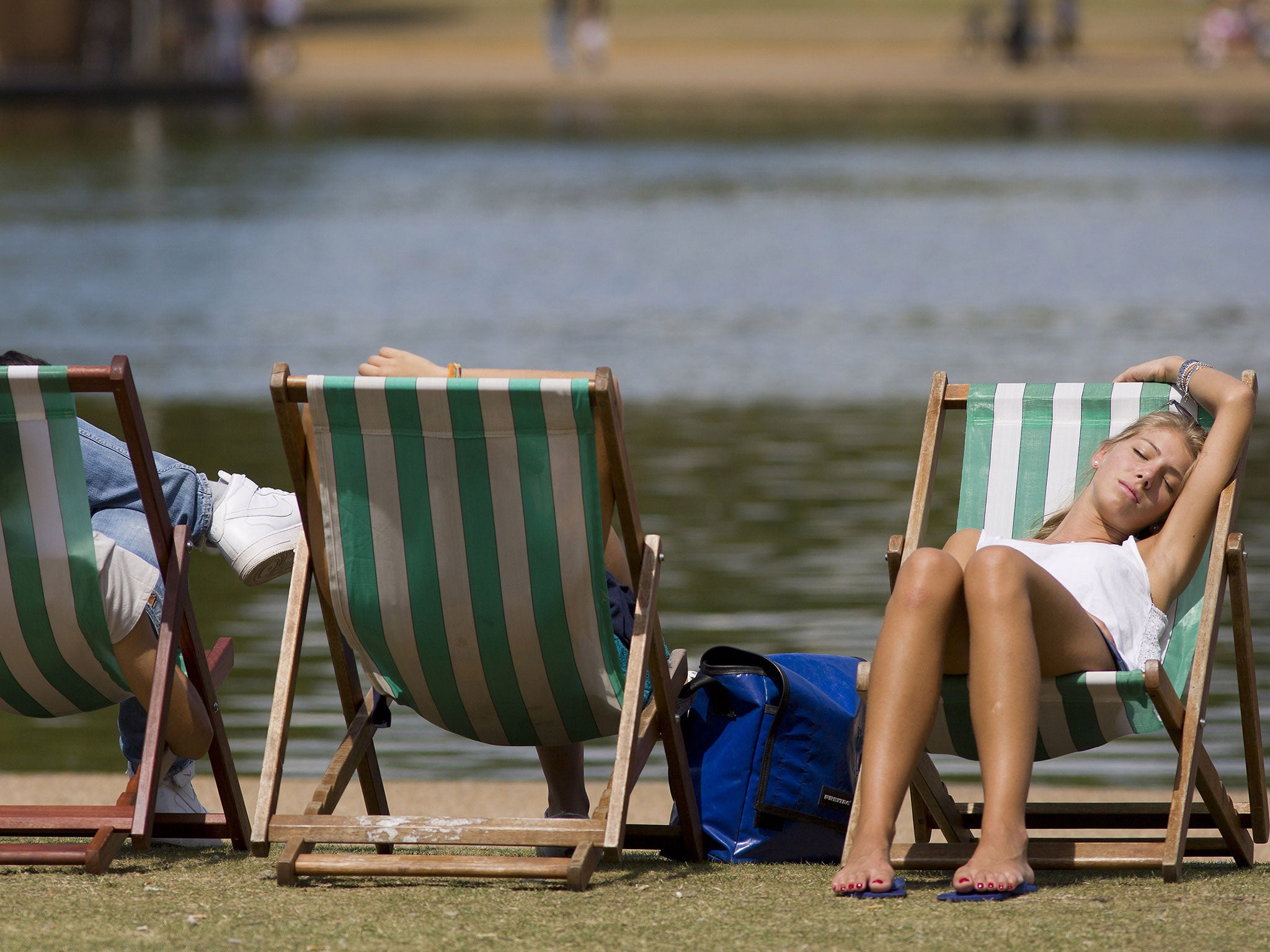 A woman rests on a deckchair by the Serpentine lake in Hyde Park, central London as England basks in warm weather