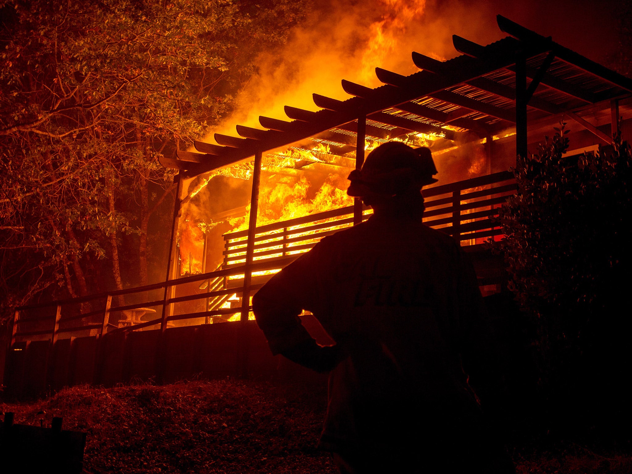 A firefighter looks on while a house is engulfed in flames during the Valley fire in Seigler Springs, California on September 13, 2015.