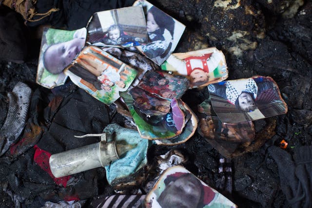 Photos of the Dawabsheh family lie in a burnt pile among the ruins of their house