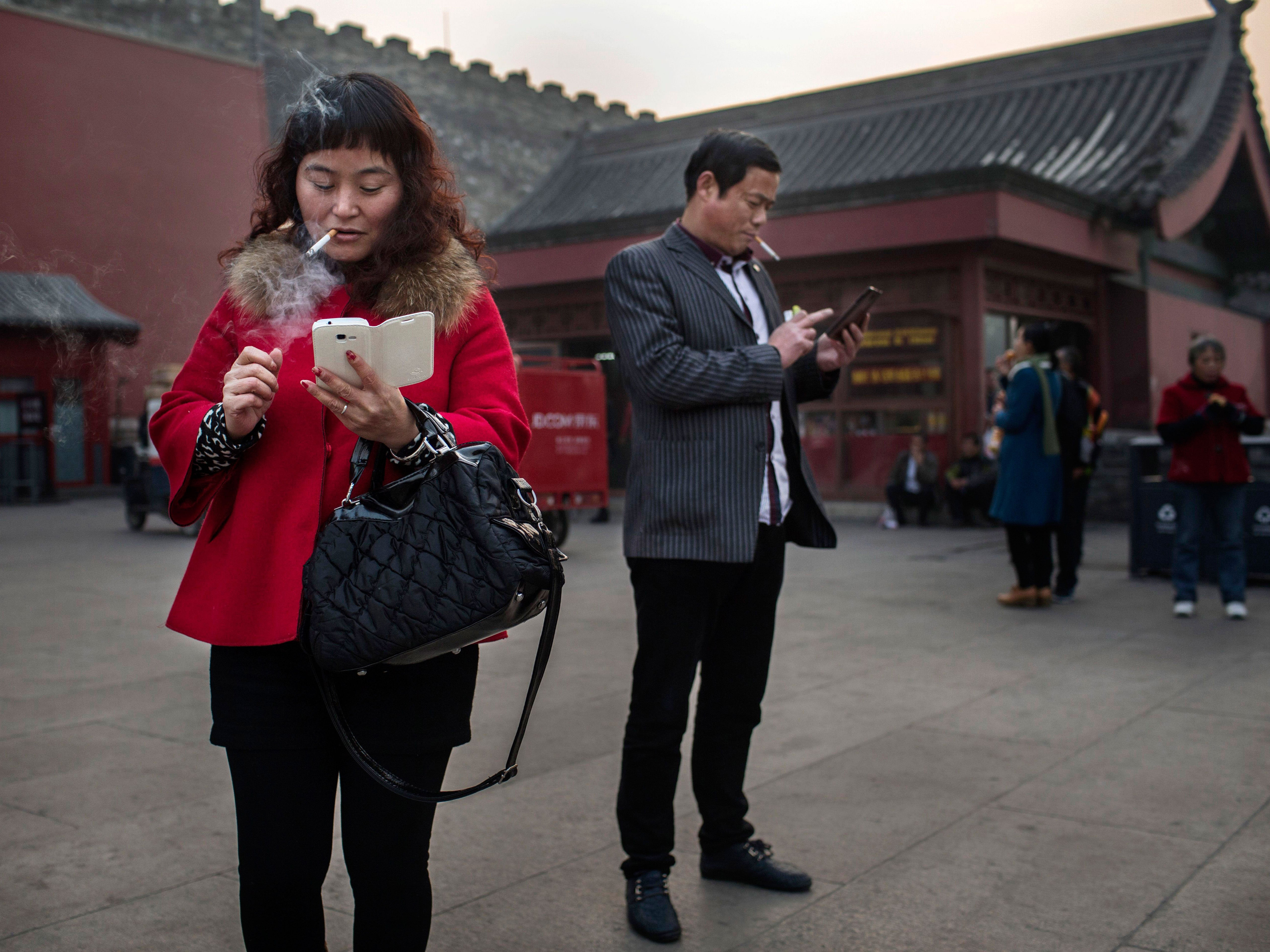 A Chinese man and woman use their smartphones on November 20, 2014 in Beijing, China