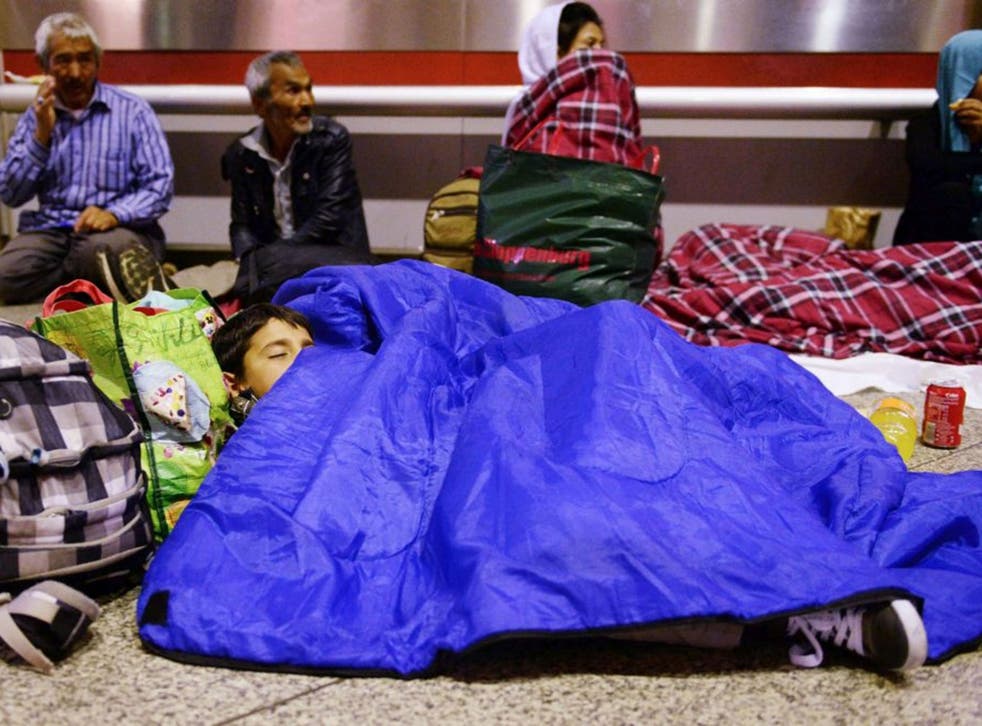 A refugee child from Afghanistan sleeps in the main hall of the train station in Munich, Germany, late 10 September 2015, as in the background other refugees are sitting. Germany expects 800,000 asylum seekers this year, four times more than last year and