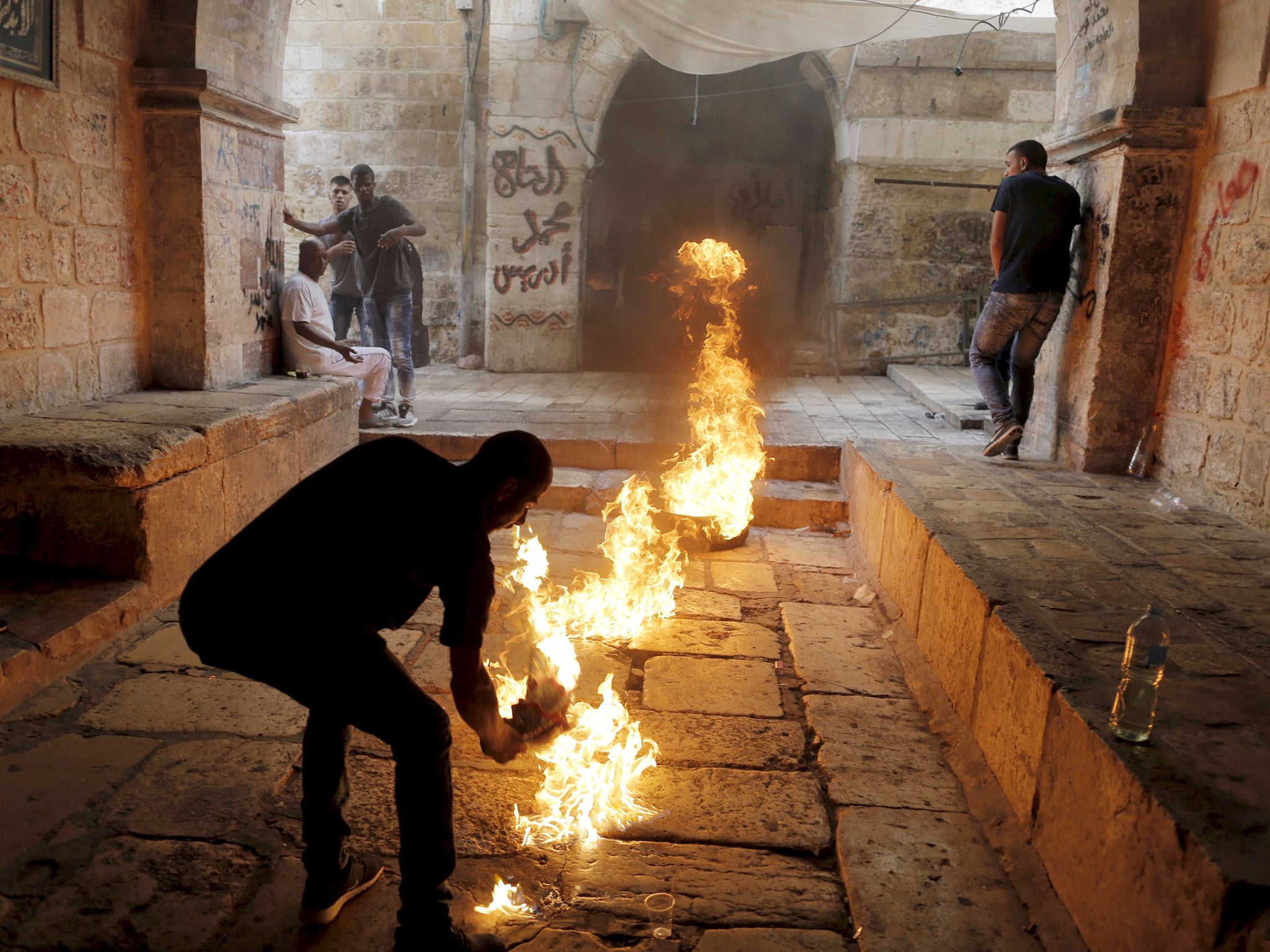 A Palestinian protester kicks a burning tyre during clashes between Palestinians and Israeli police officers in Jerusalem's Old City