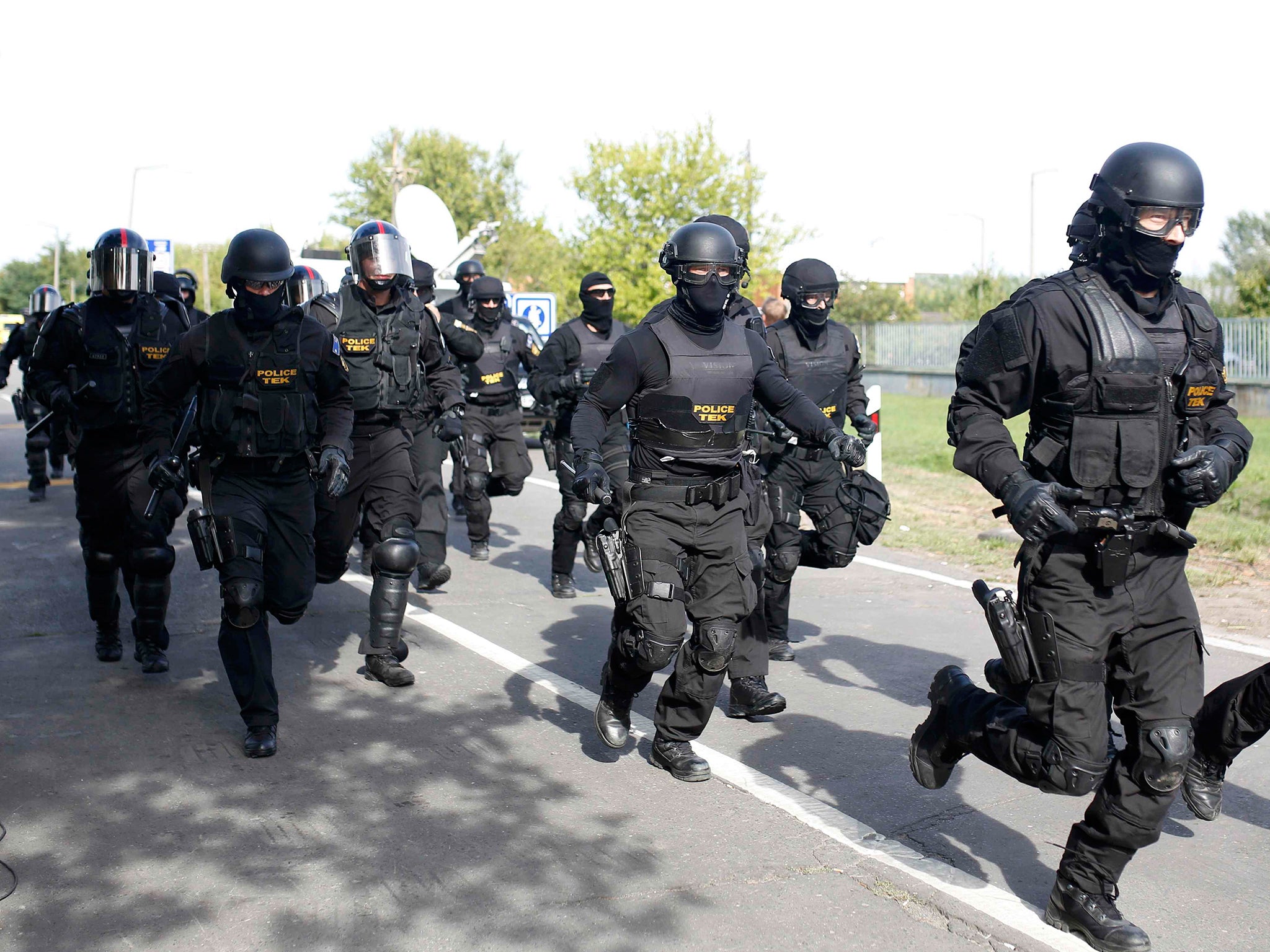 Hungarian riot policemen run as they are deployed at the border crossing with Serbia in Roszke