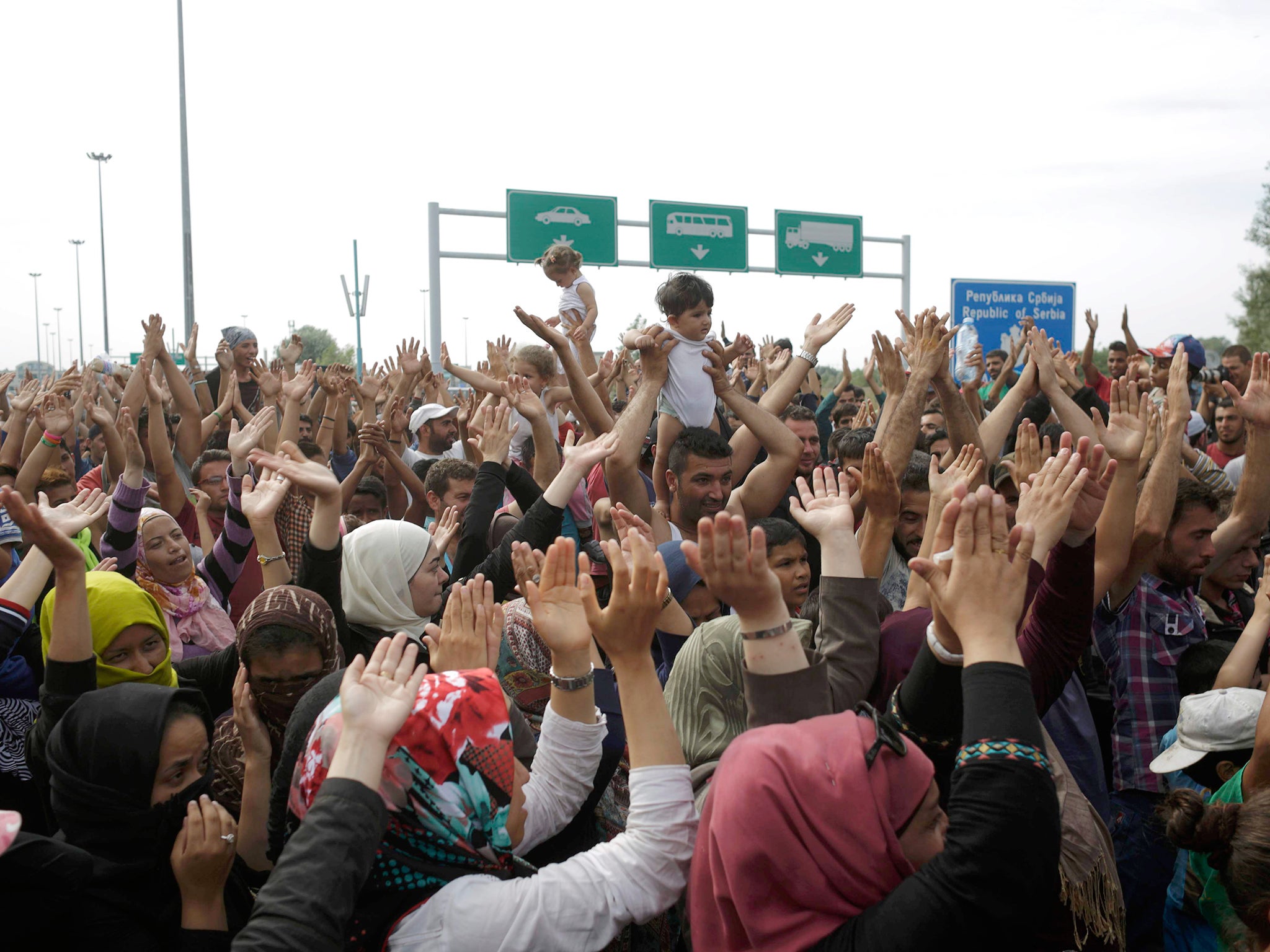 Migrants shout slogans as they stand in front of a barrier at the border with Hungary near the village of Horgos, Serbia