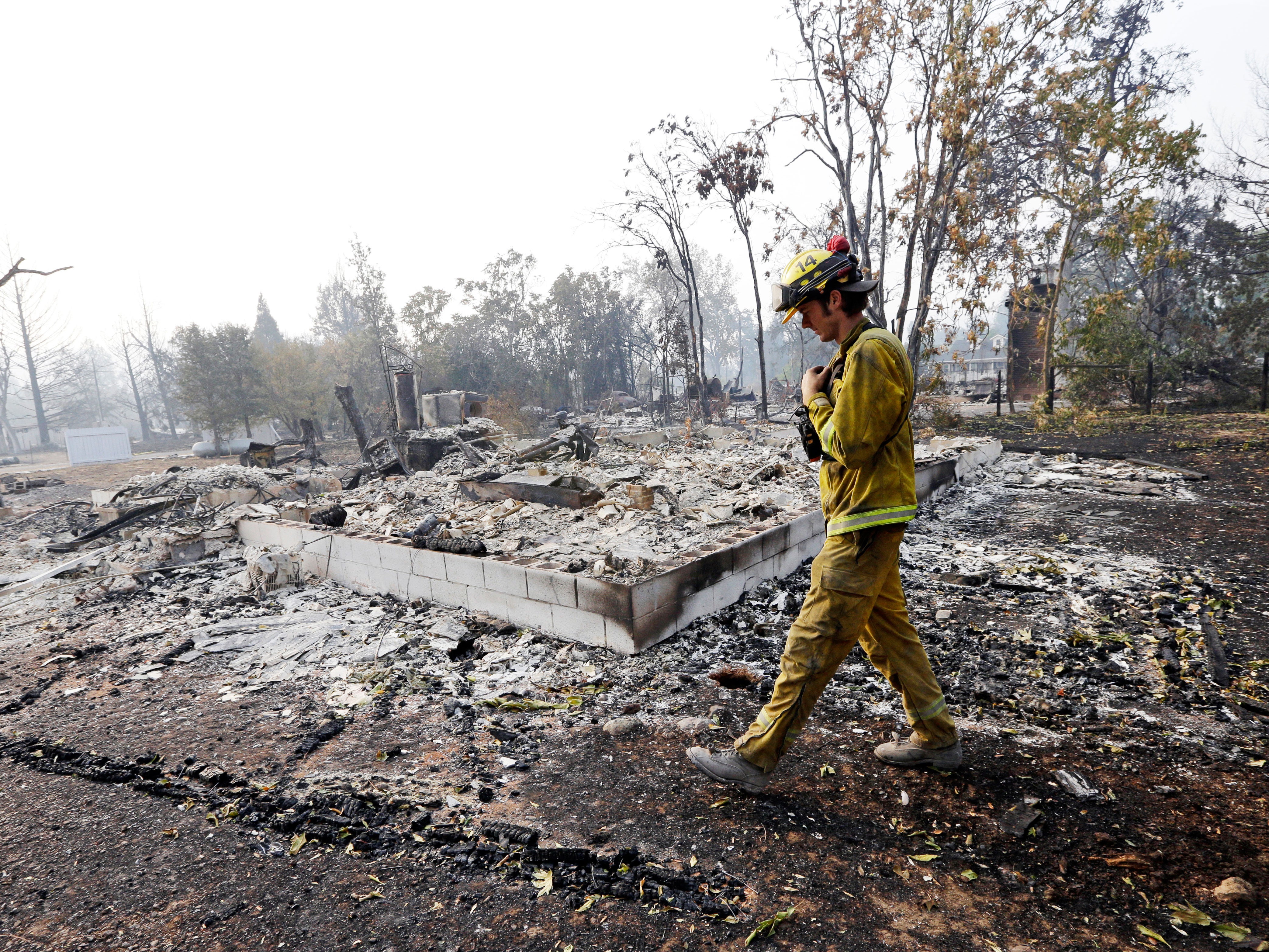 A firefighter walks past the remains of a house destroyed in a wildfire