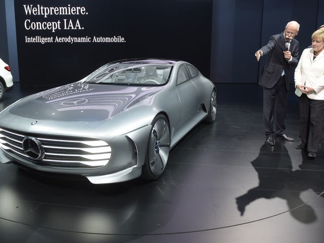 Daimler CEO Dieter Zetsche (L) presents a concept car to German Chancellor Angela Merkel during her visit to the booth of German car maker Daimler on the opening day of the Frankfurt Motor Show IAA in Frankfurt