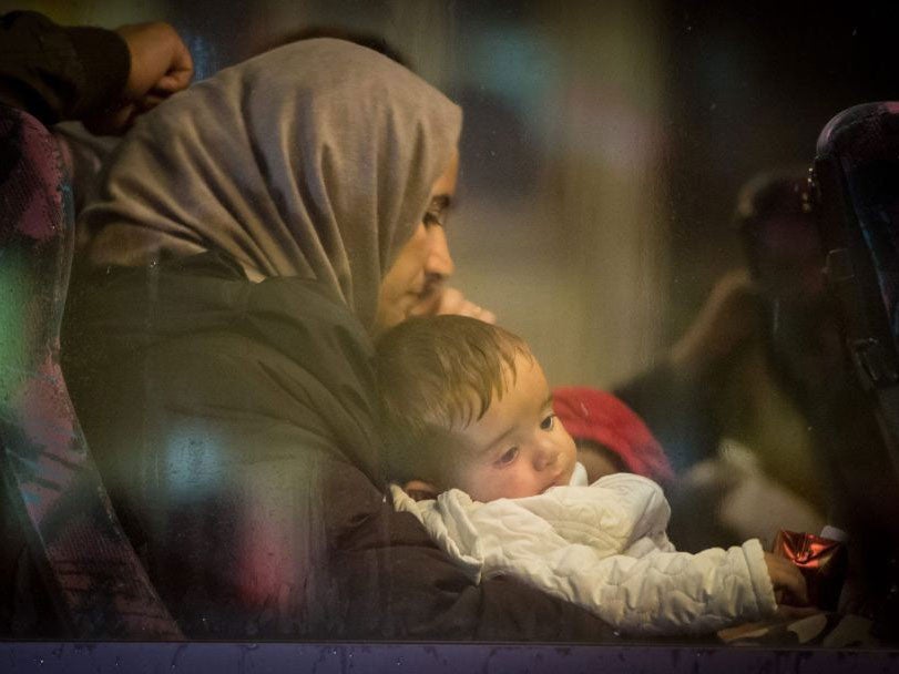 A refugee mother waits with her child in a bus after arriving in Germany