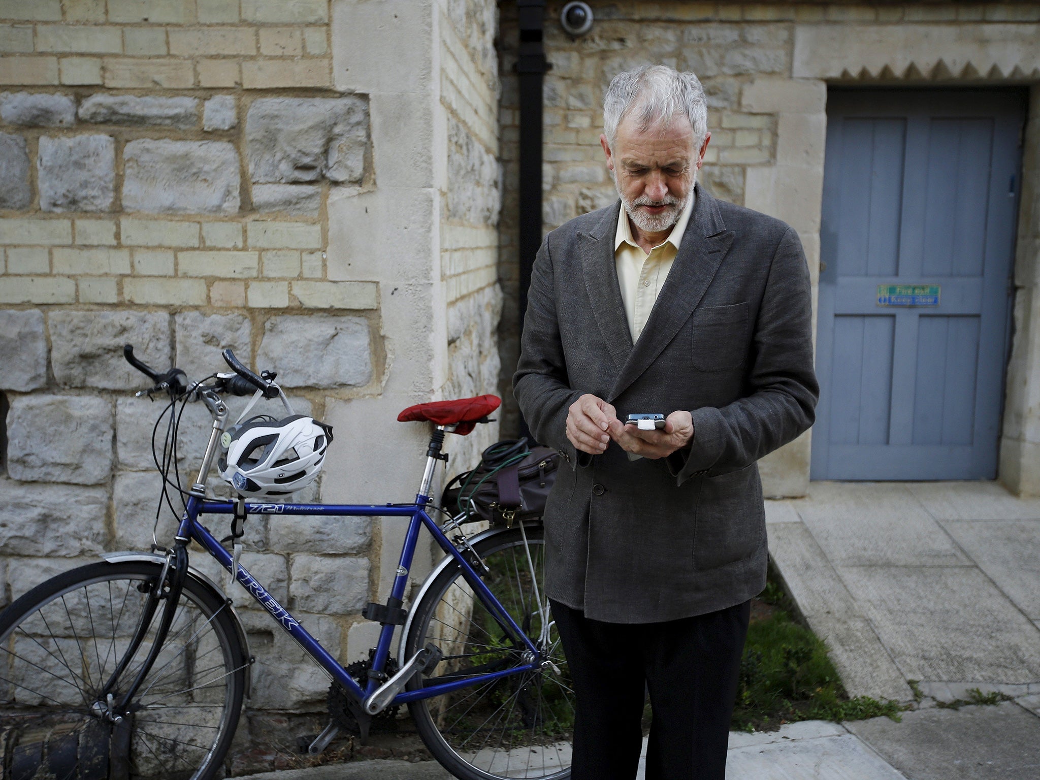 Labour Party leader Jeremy Corbyn checks his phone after arriving on his bicycle for a rally in London (Reuters)
