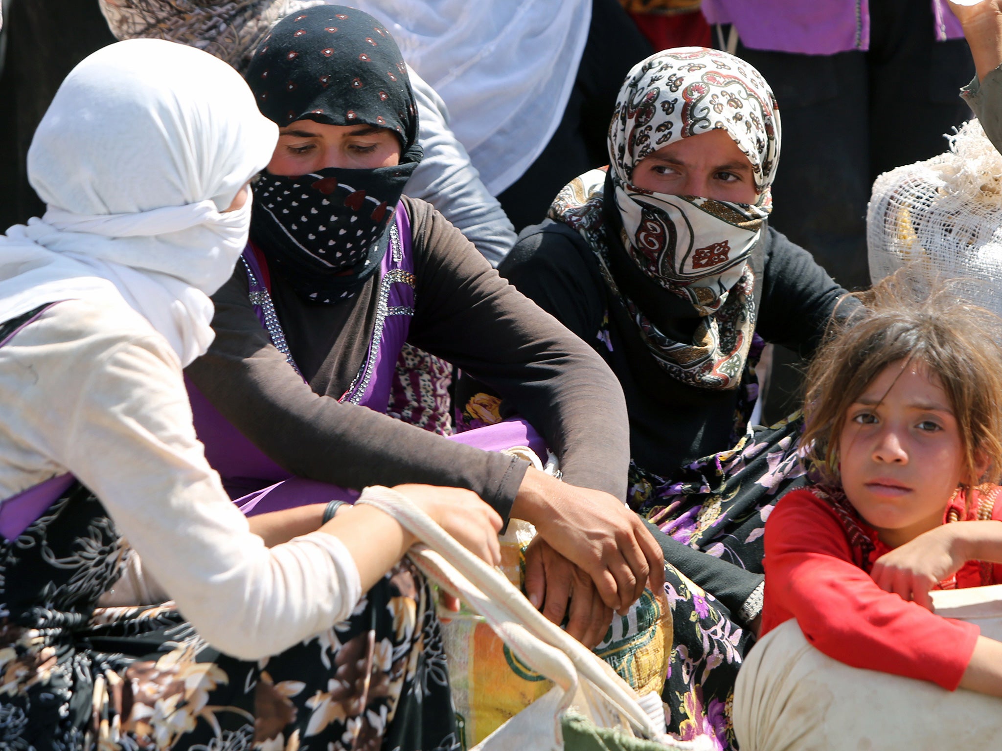 Iraqi Yazidi women gather sitting at the Bajid Kandala camp near the Tigris River