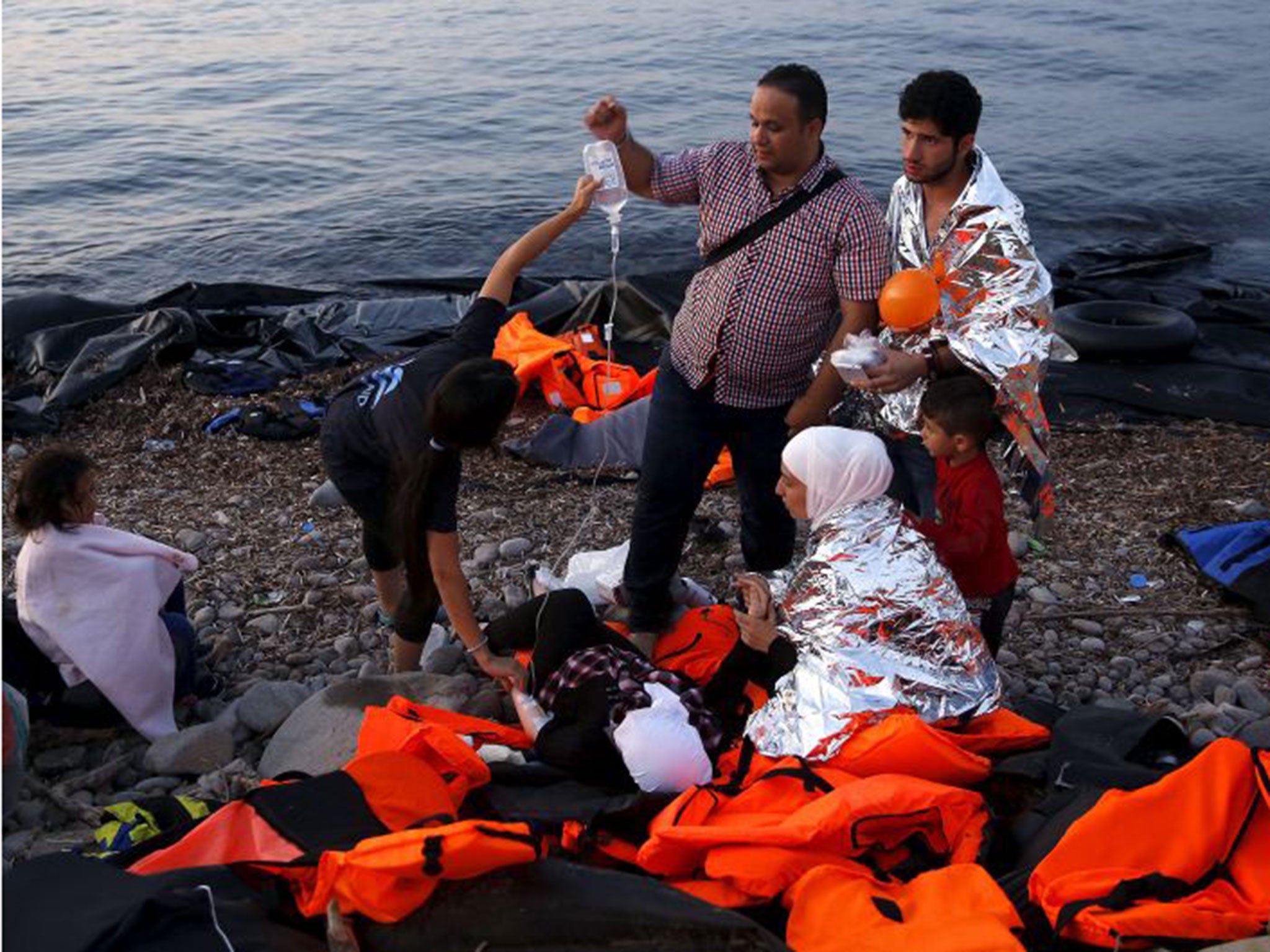 Volunteers provide medical help to a pregnant Syrian refugee woman shortly after she arrived on Lesbos (Reuters)