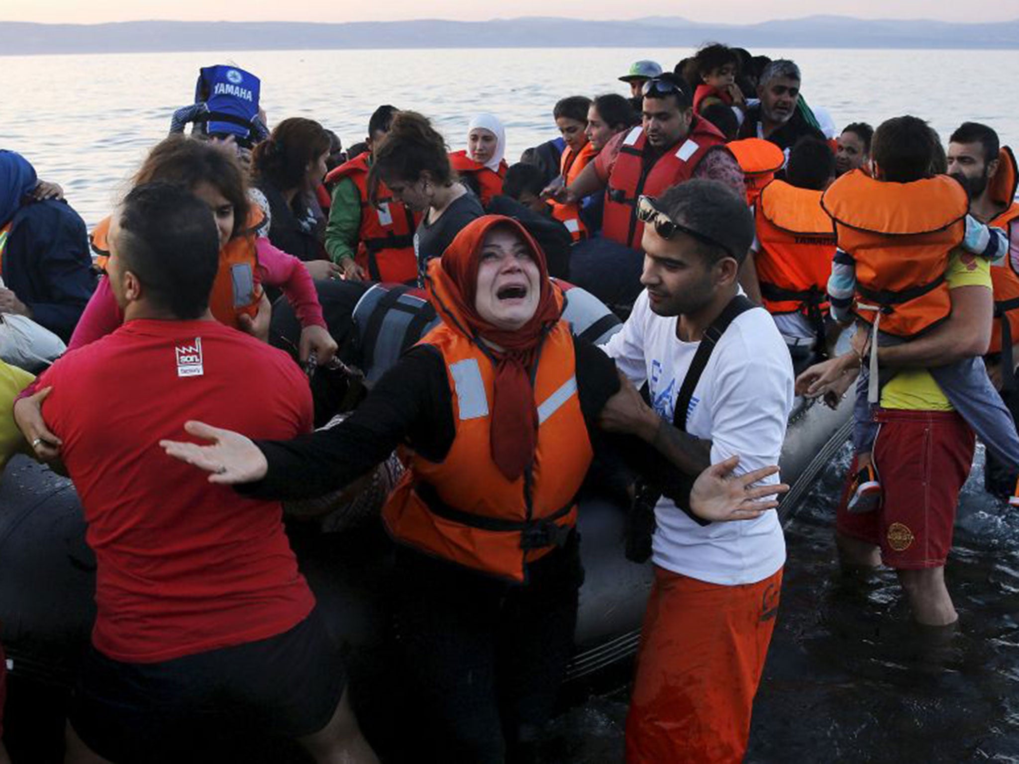 A Syrian refugee reacts as she and family members jump off a overcrowded dinghy after landing safely on the Greek island of Lesbos (Reuters)