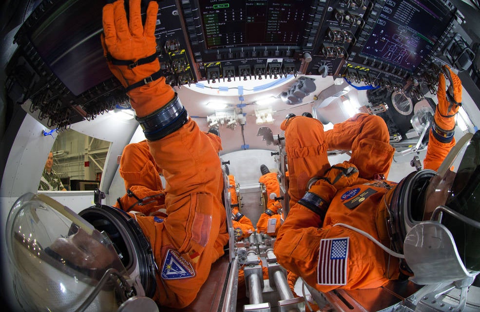 Spacesuit engineers show how astronauts would sit inside the Orion capsule, in a mockup of the vehicle