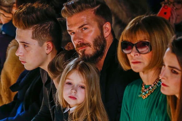 Former England captain David Beckham sits next to U.S. Vogue editor Anna Wintour (2nd R) with his daughter, Harper, on his lap and son Brooklyn (L) during a presentation of the Victoria Beckham Fall/Winter 2015 collection during New York Fashion Week Febr