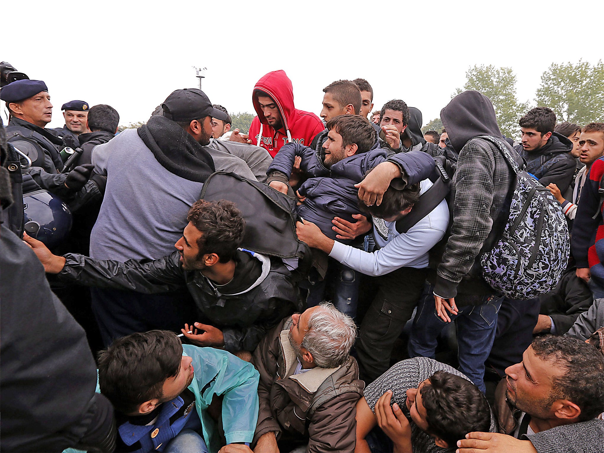 Refugees try to push the police on the entrance of a registration camp in the village of Opatovac
