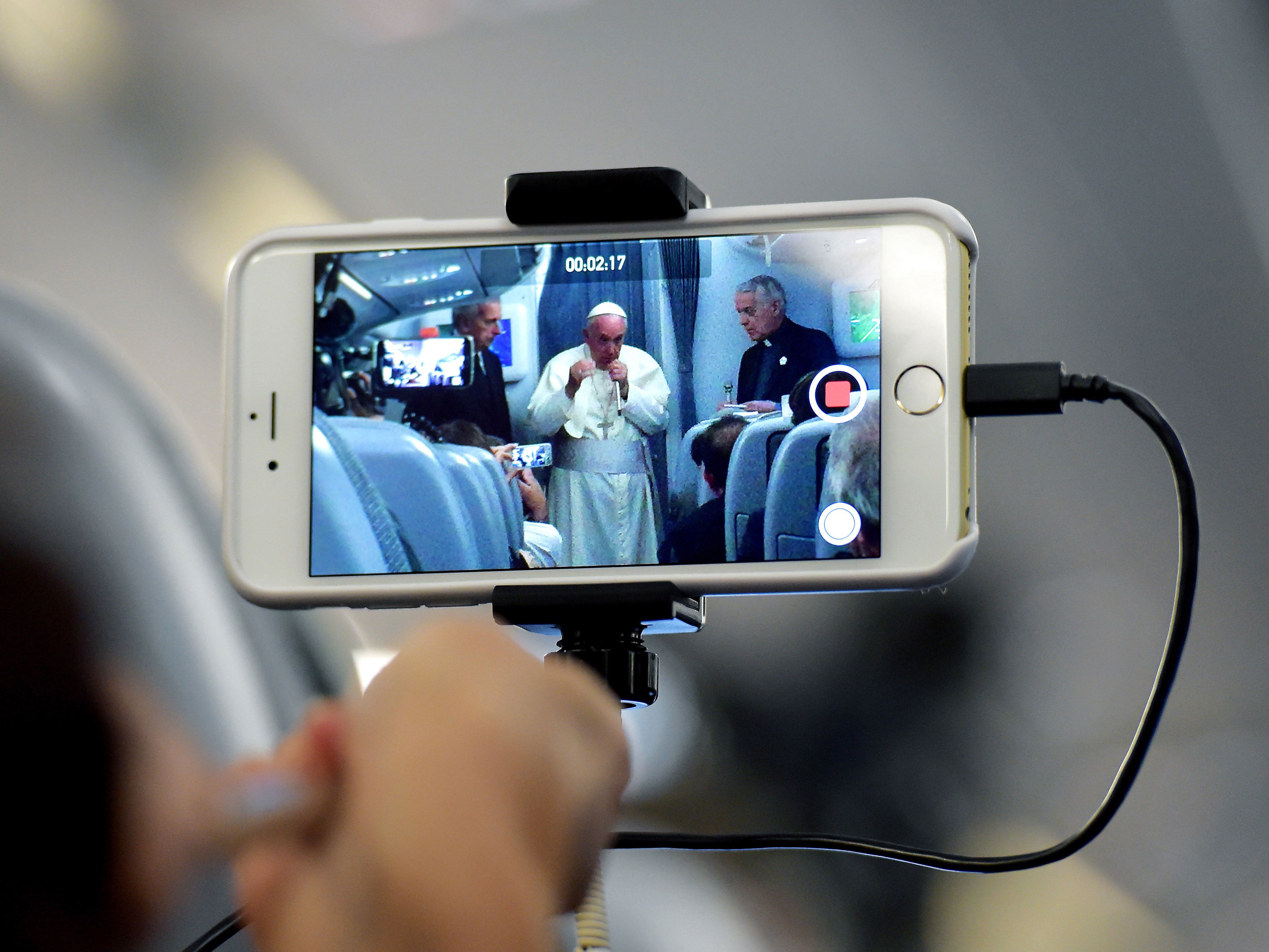 A journalist takes with his mobile phone a picture of Pope Francis during a press conference on July 13, 2015, onboard a plane on his way back to Rome from Paraguay, the final stop of his South America tour