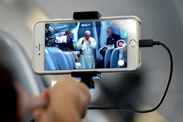 A journalist takes with his mobile phone a picture of Pope Francis during a press conference on July 13, 2015, onboard a plane on his way back to Rome from Paraguay, the final stop of his South America tour