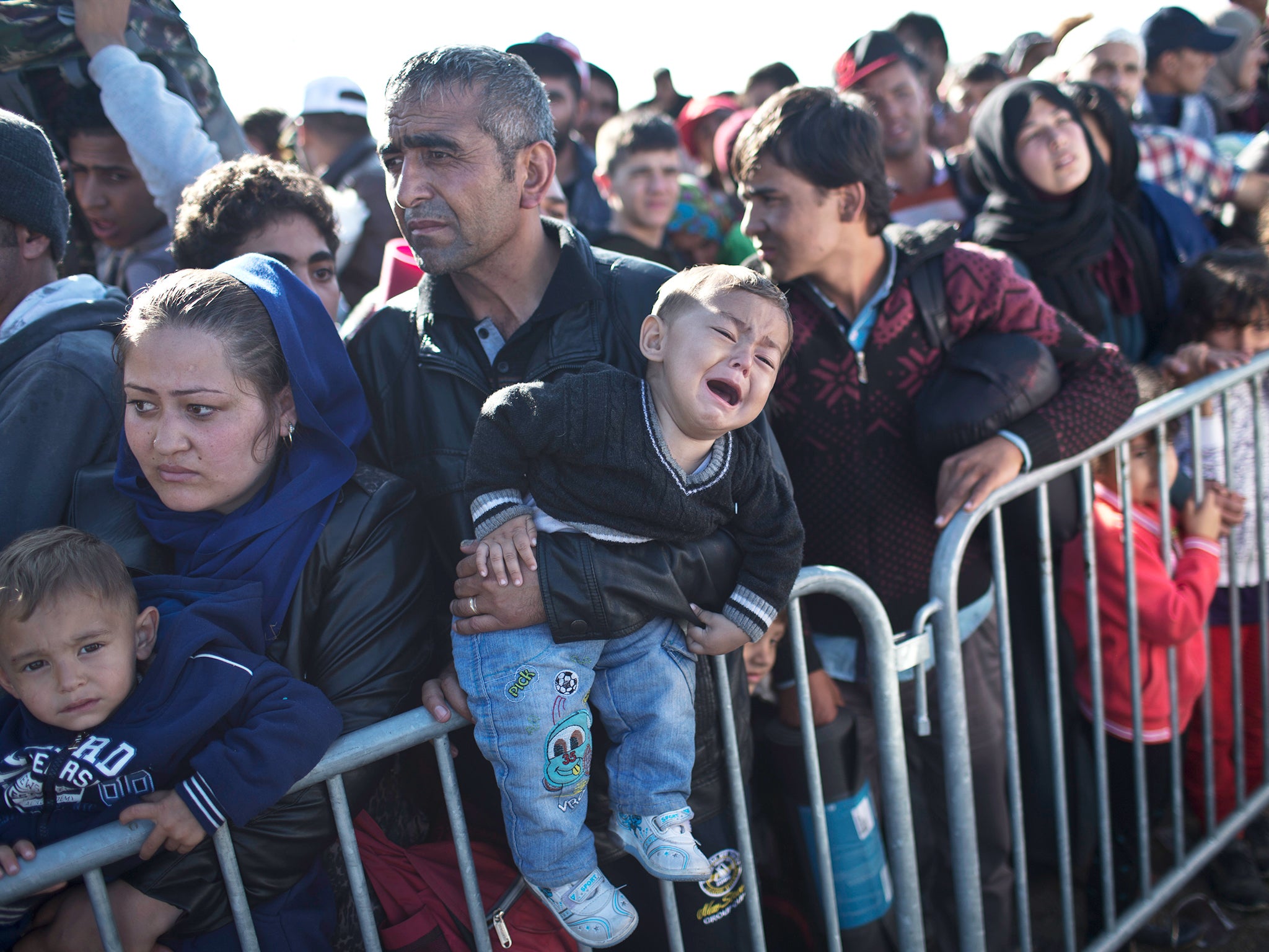 A child cries as his family wait in line in order to get into a reception center for refugees in Opatovac, Croatia