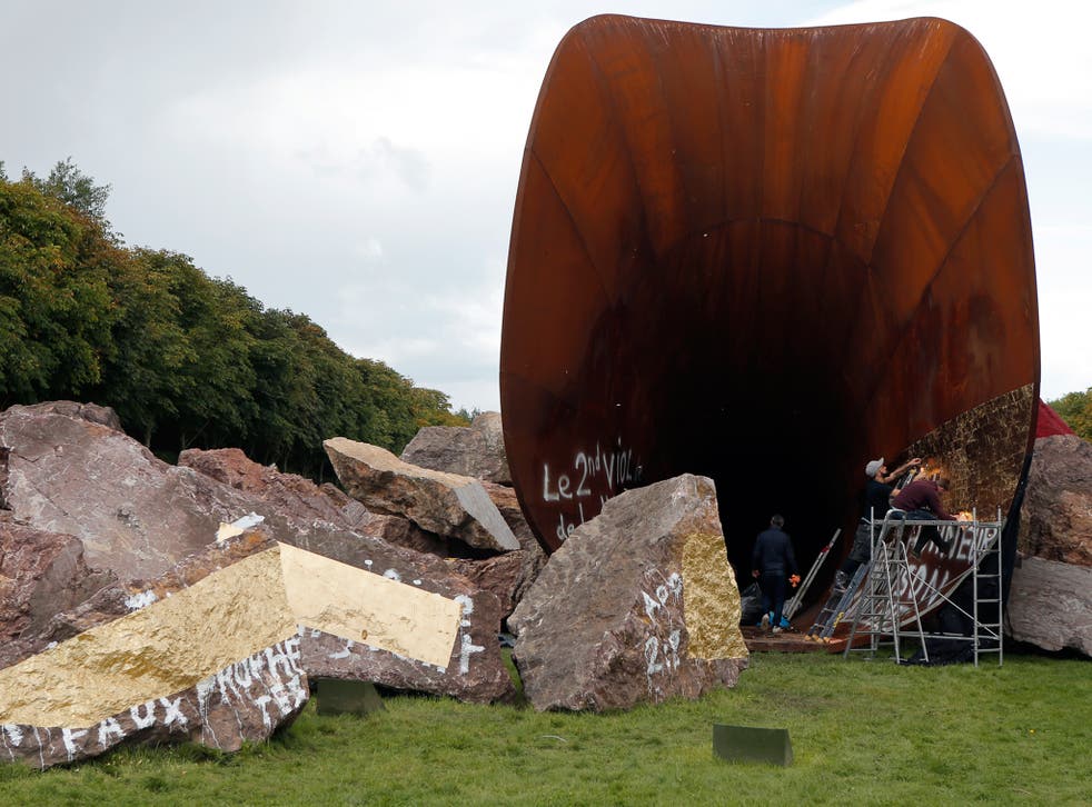 Art assistant workers cover up with gold leaf to mask anti-Semitic graffiti on the vandalized sculpture "Dirty Corner" by British-Indian artist Anish Kapoor in the Versailles castle in Versailles, outside Paris, France. The controversial red trumpet-shape