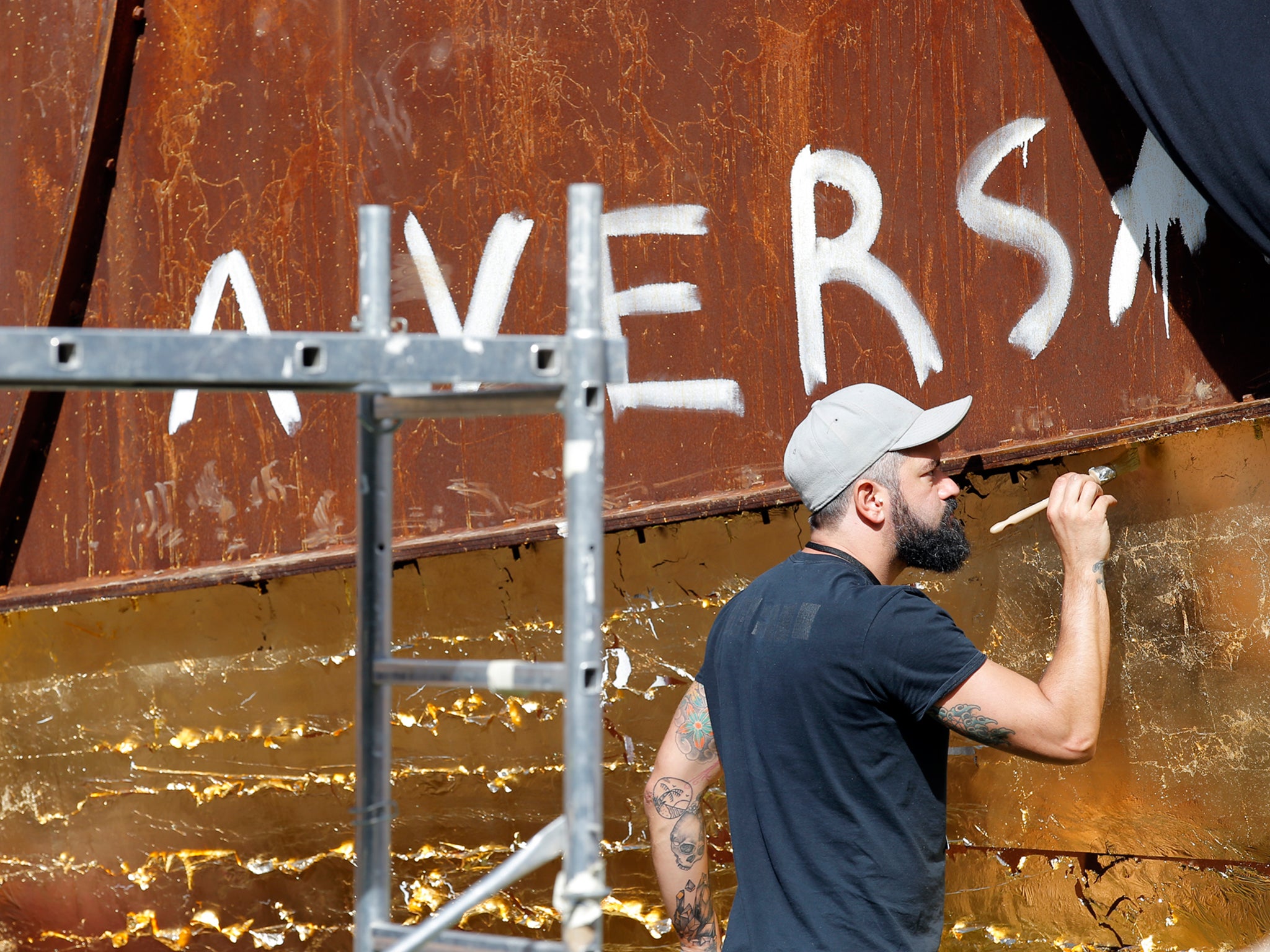 Art assistant worker covers up with gold leaf to mask anti-Semitic graffiti on the vandalized sculpture "Dirty Corner" by British-Indian artist Anish Kapoor in Versailles