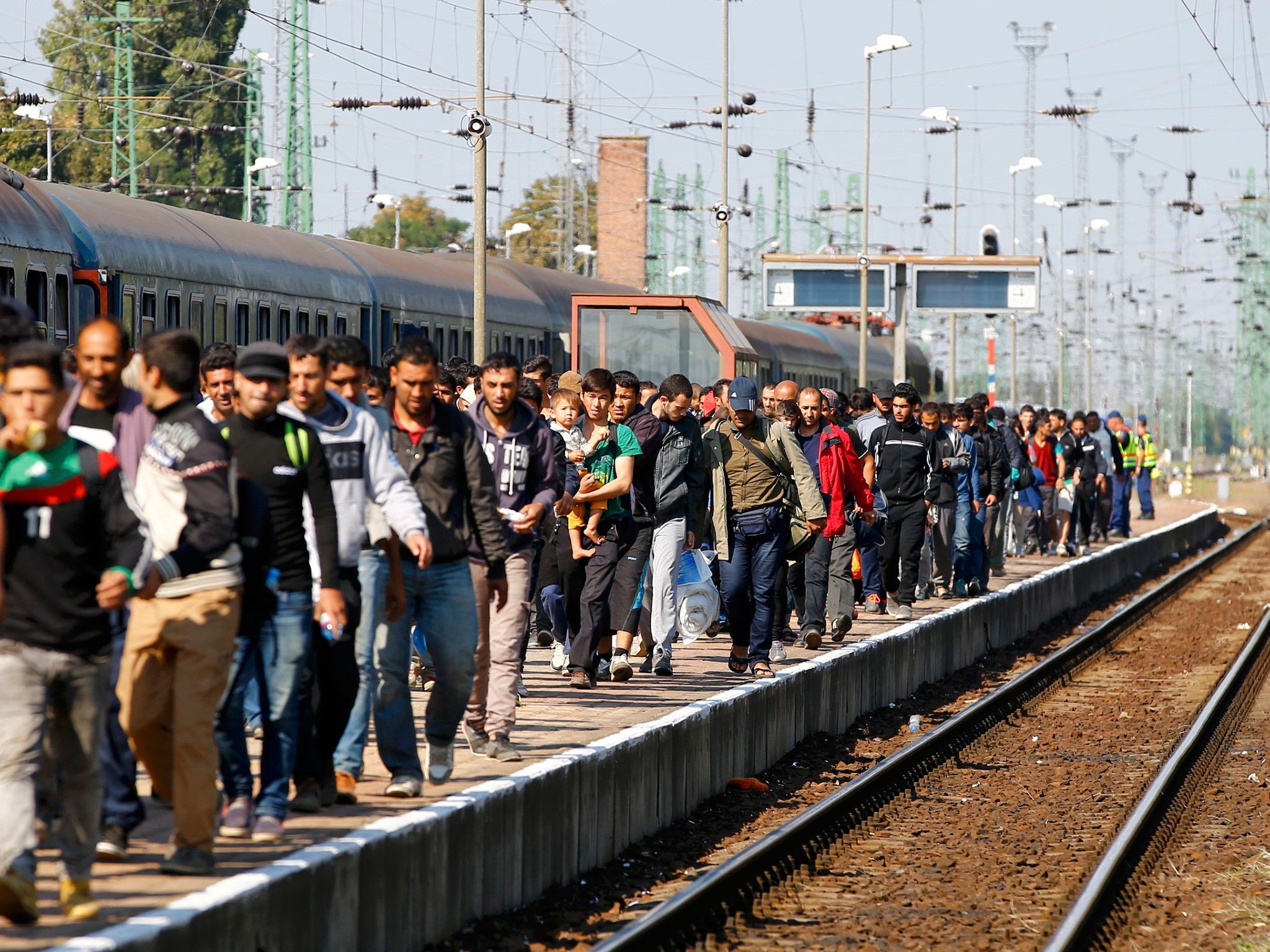 Refugees walk along a railway platform after they arrived by train in Hegyeshalom, Hungary