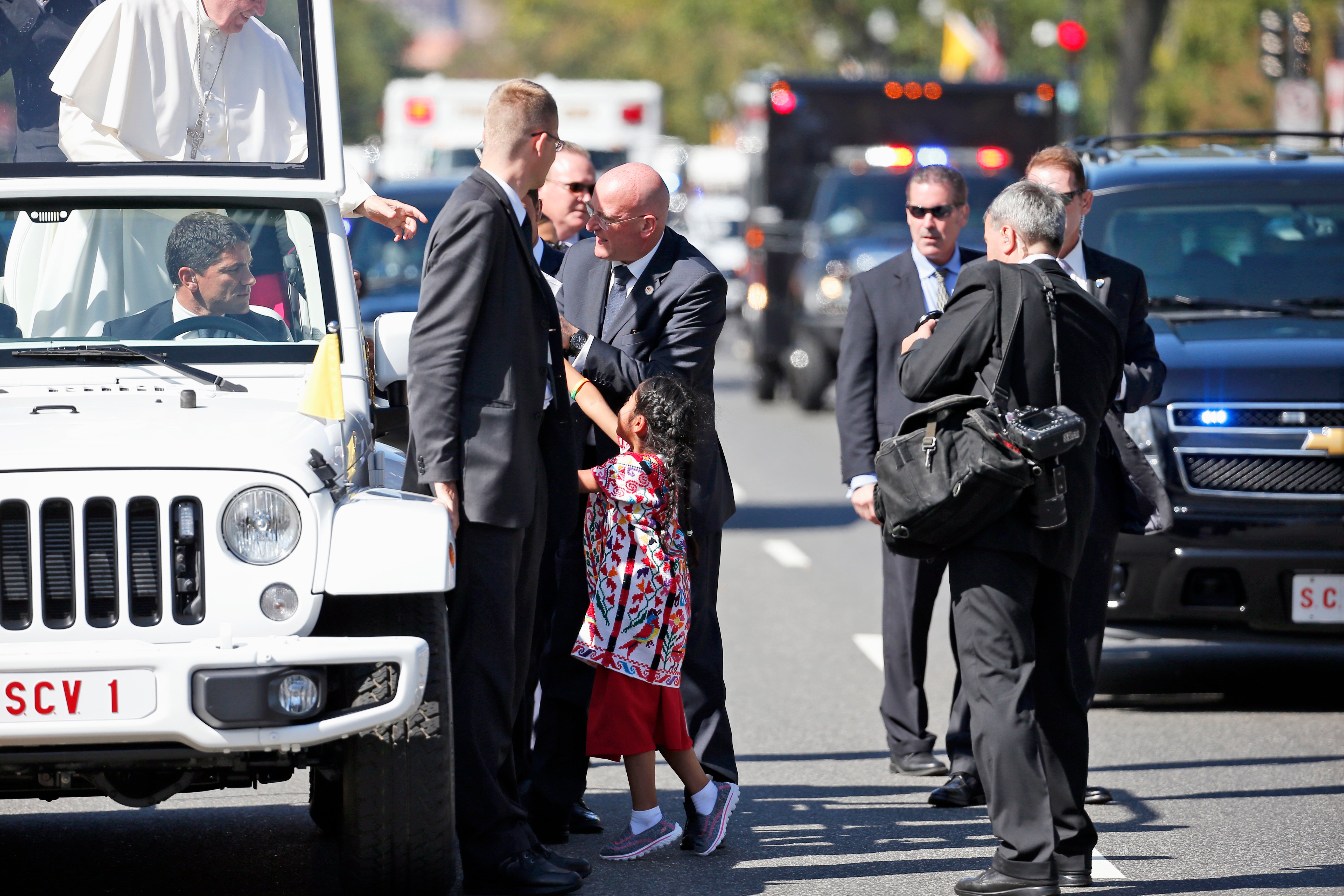 Sophie Cruz, 5, is escorted by security as she hands Pope Francis a gift. (Alex Brandon/Associated Press)