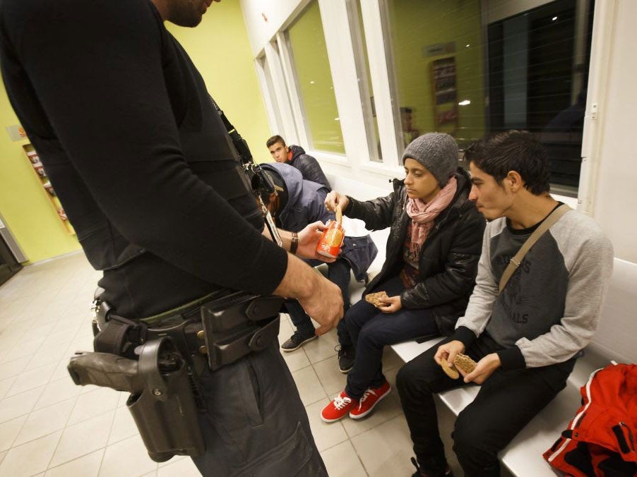 A Norwegian police officer serving biscuits to refugees Hussain (L-R), Ahmed, Anoud and Mustafa in the Police Immigration in Svinesund, Norway, 10 September 2015.