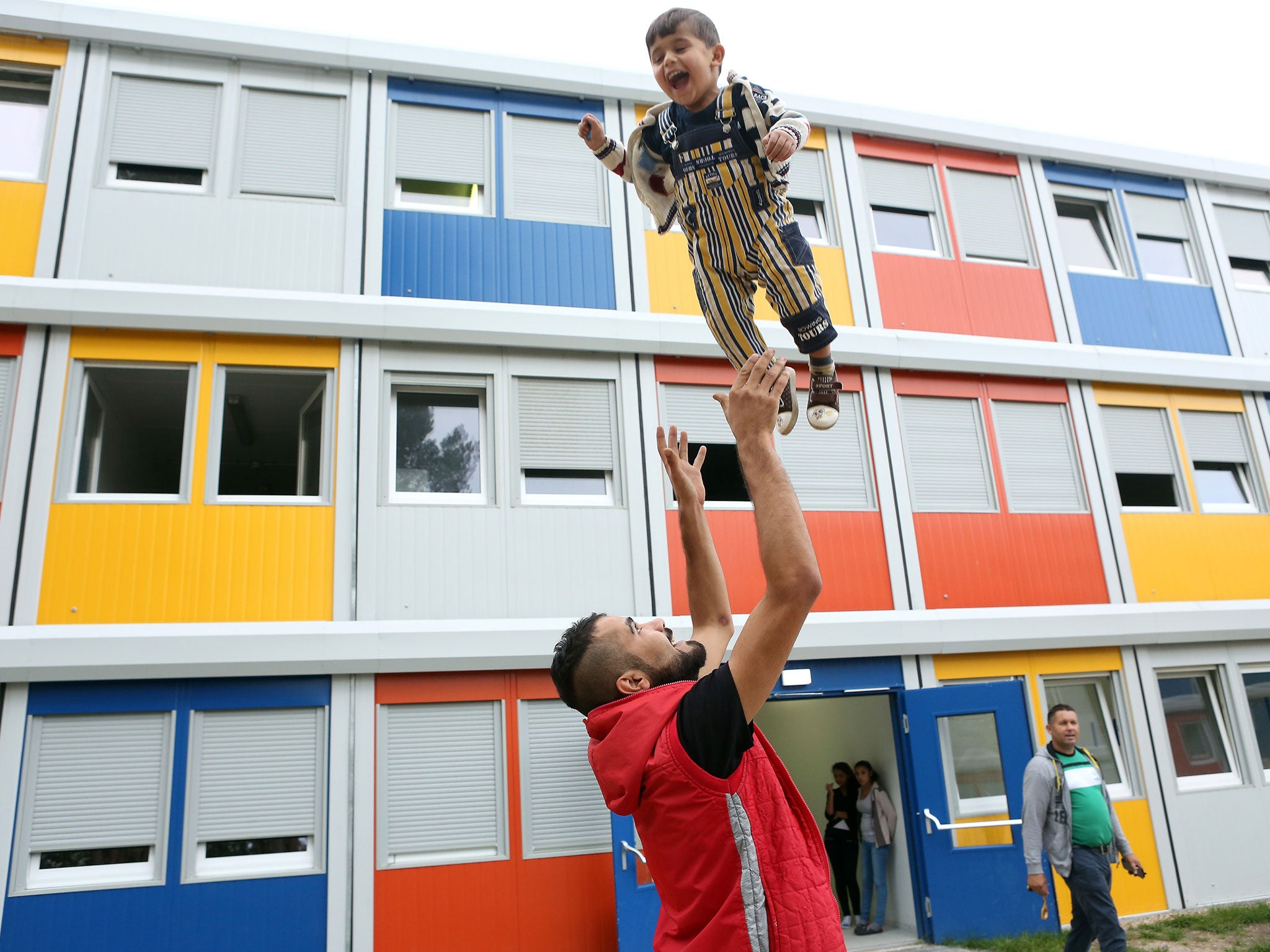 A Syrian refugee plays with his child at a temporary shelter made from shipping containers in Berlin